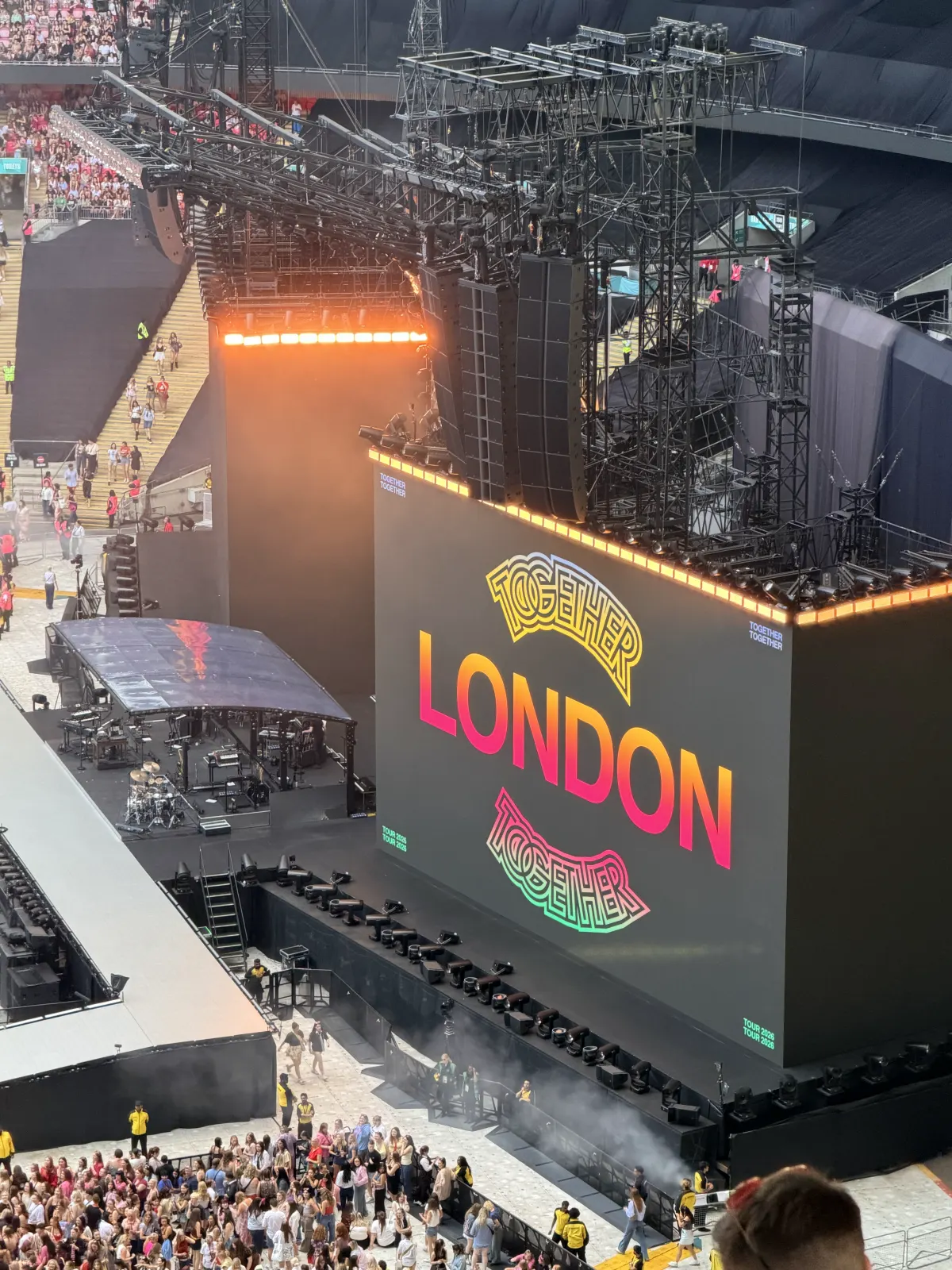 Looking down from high in Wembley Stadium at the Together, Together stage before the show, a huge screen reading London between two Together logos, fans filling the pitch below.