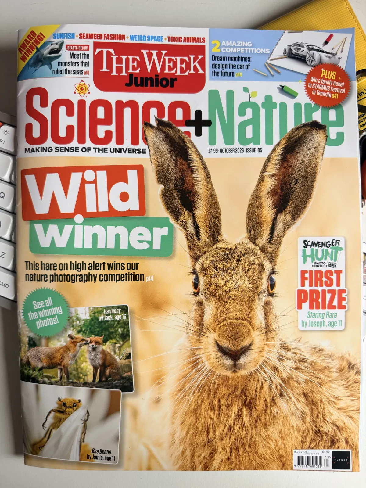 The October 2026 issue of The Week Junior Science+Nature on a desk beside a keyboard, a close-up of a hare on the cover under the line 'Wild winner'.